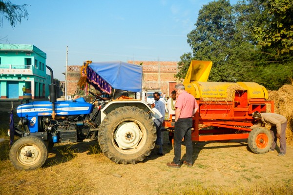 Alfred Schmidley ’85 talks to a contractor who travels to farms after harvest to provide mobile threshing services for a fee or portion of the output. This option avoids paddy sitting in the field or homestead (exposed to elements, re-wetting, pests, etc.) for prolonged periods while also freeing up family labor for other activities.
